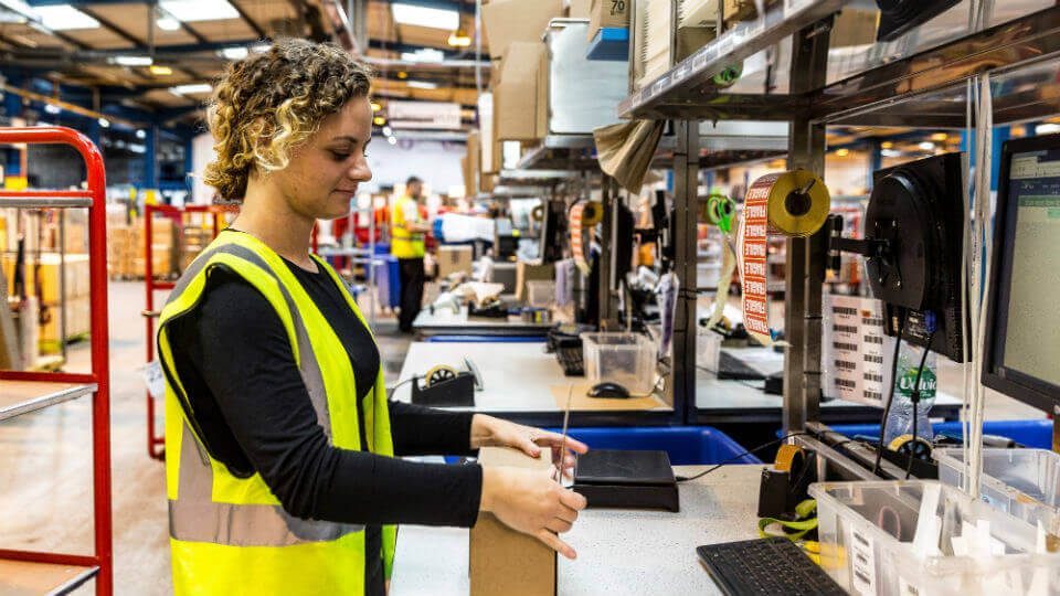 A UK fulfilment services team member packs an item in a box, as part of the order fulfilment process