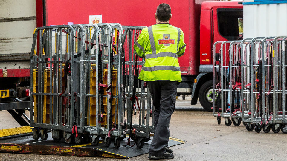 A Royal Mail worker loads trolleys onto a van, as part of the order fulfilment process