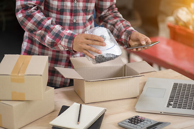 A small business owner packing and shipping their own orders manually