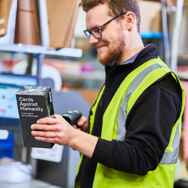 A James and James team member scans a Cards Against Humanity box at a packing desk