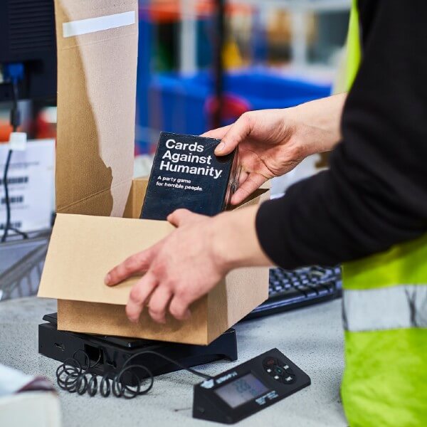 A James and James team member packs a Cards Against Humanity box as part of the fulfilment process