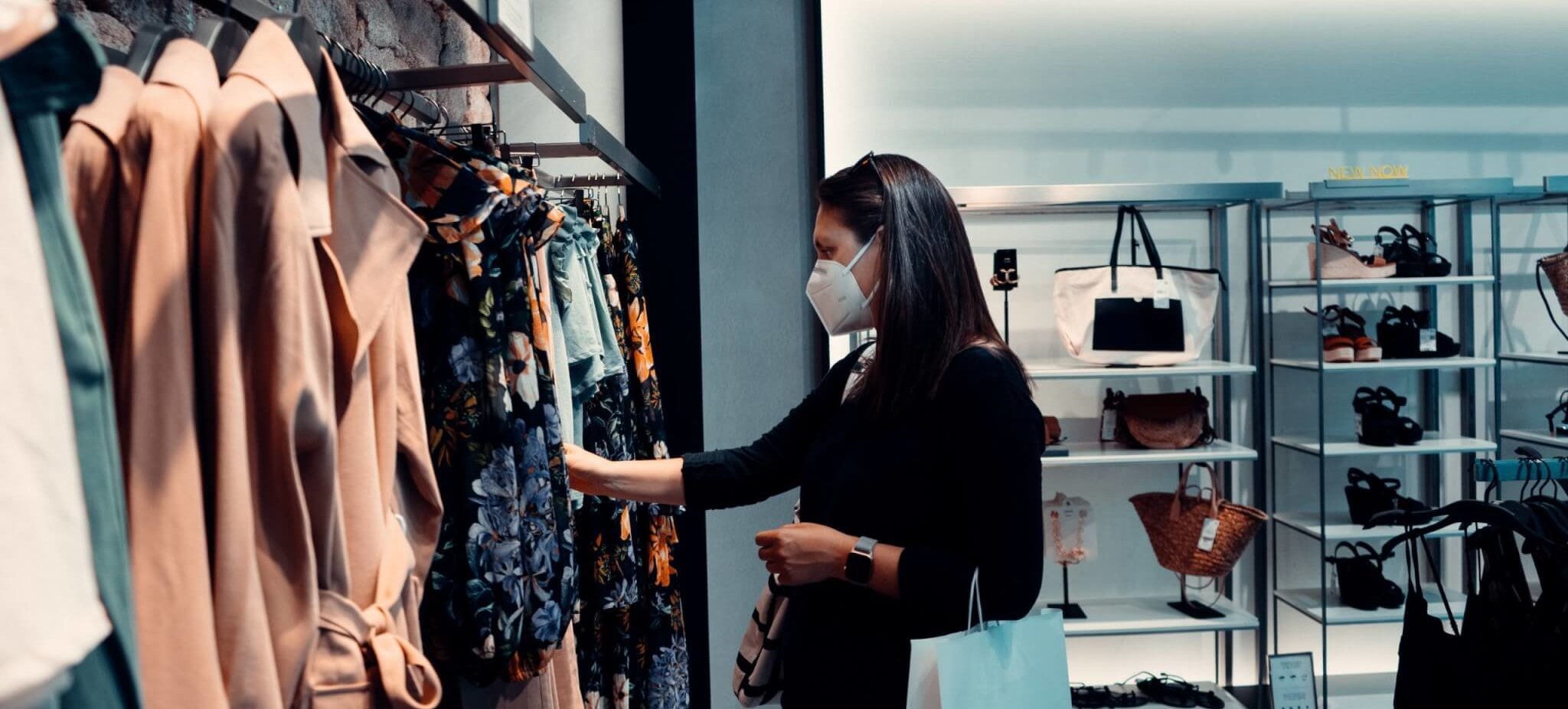 A woman shopping in a clothing store wearing a mask to protect herself from covid-19